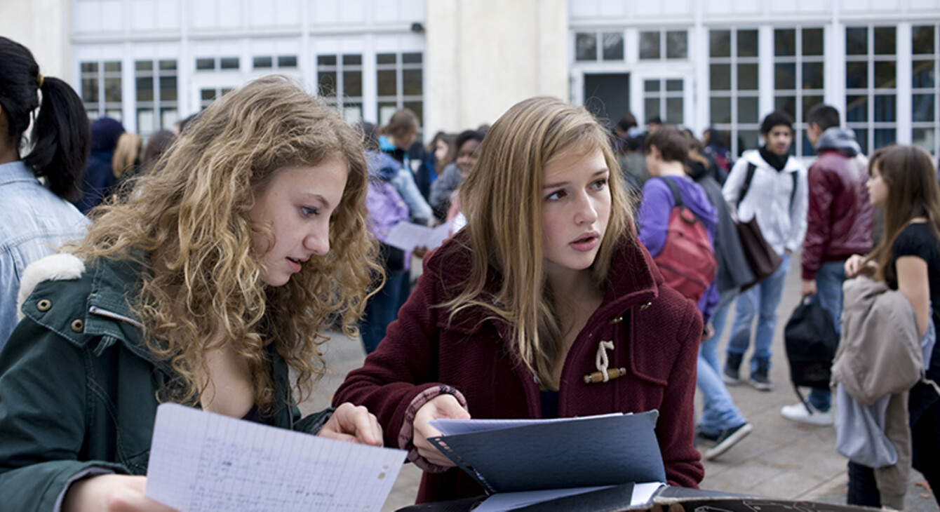 Deux élèves travaillent dans la cour du collège