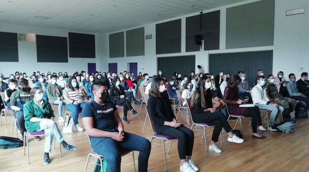 Ensemble d'élèves assis sur des chaises et écoutant le discours de la rectrice